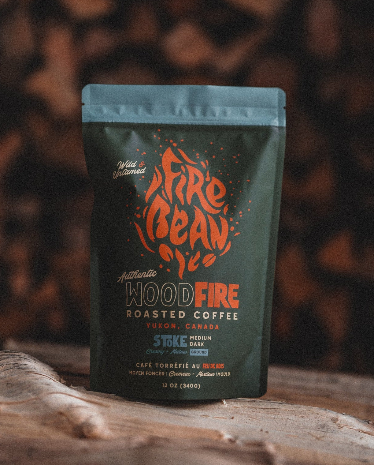Fire Bean Woodfire roasted coffee package on a wooden surface with a blurred natural background