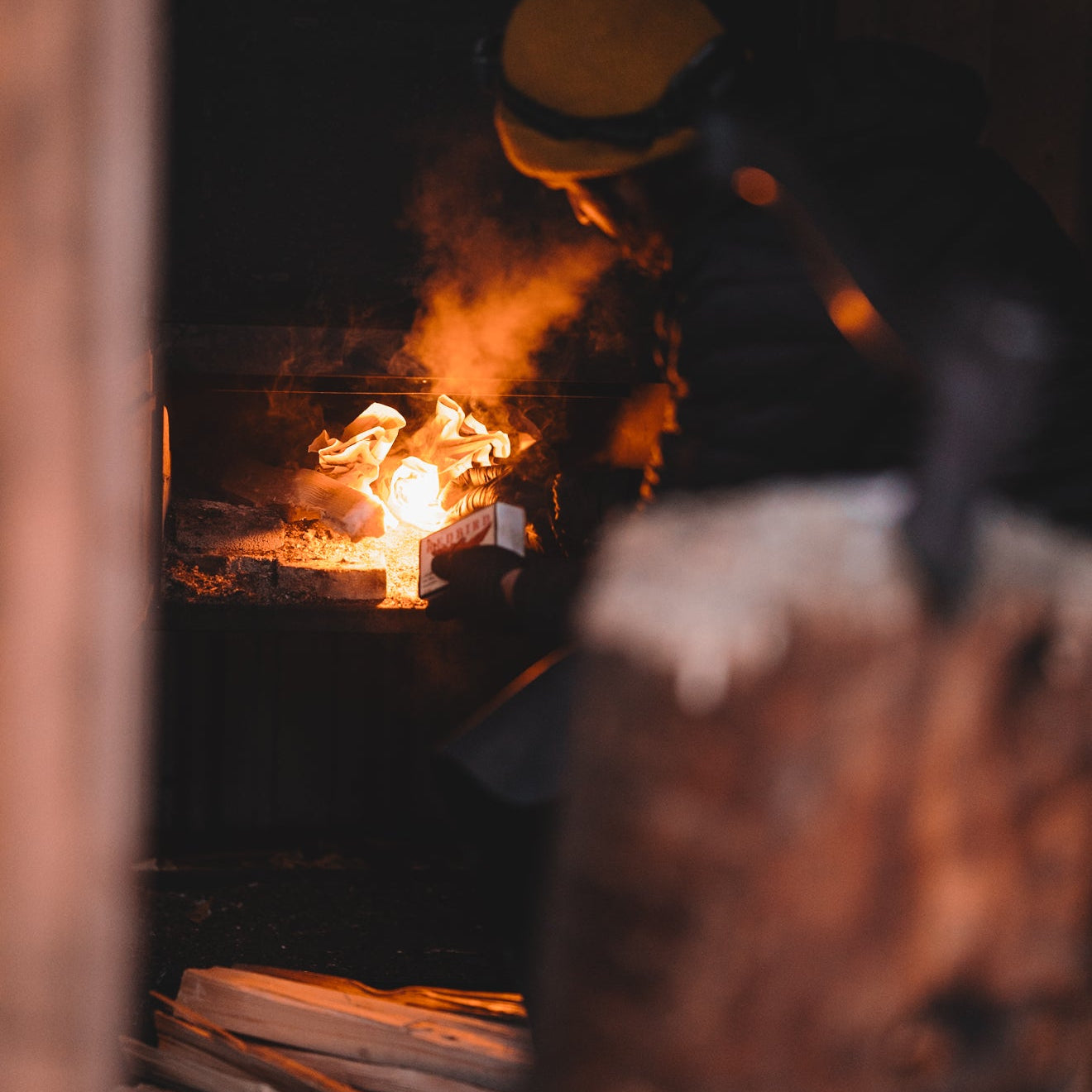 Person working with fire and tools in a dark workshop