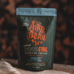 Fire Bean Woodfire roasted coffee package on a wooden surface with a blurred natural background