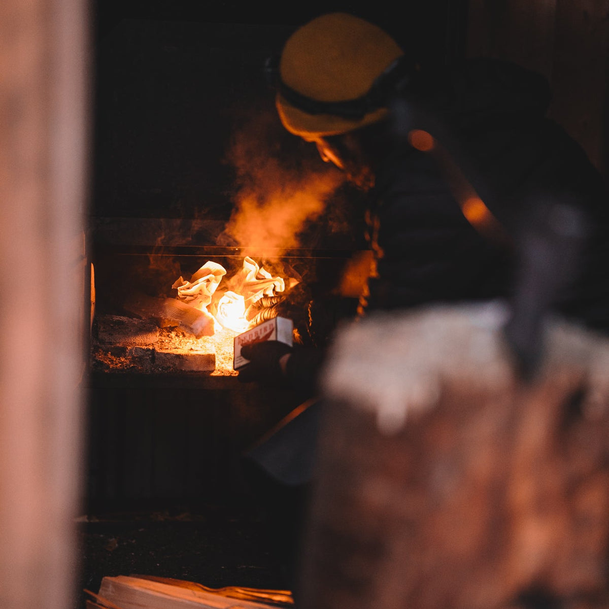 Person wearing a yellow helmet working with flames in a forge