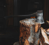 Wooden stump with a axe and stacked firewood in a dimly lit room